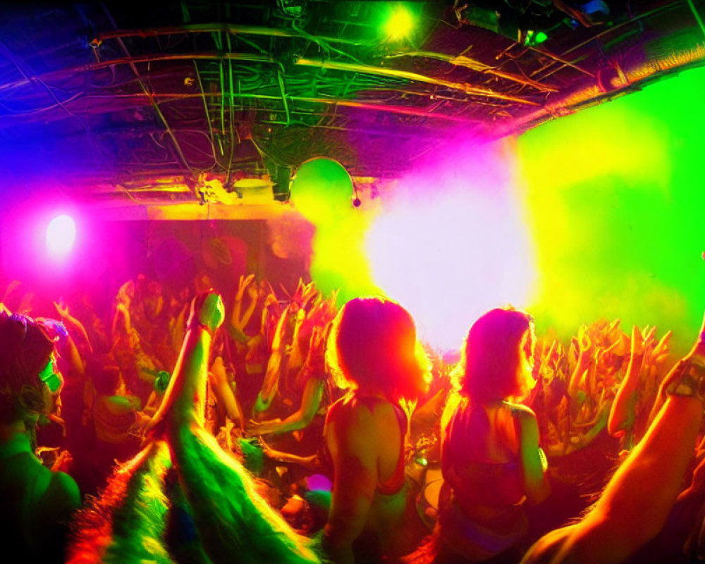Crowd dancing under green and pink lights