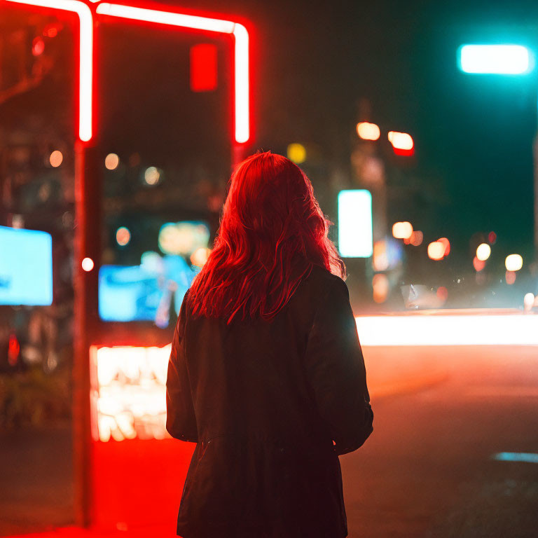 Person with Long Hair Standing at Night Under Neon Lights