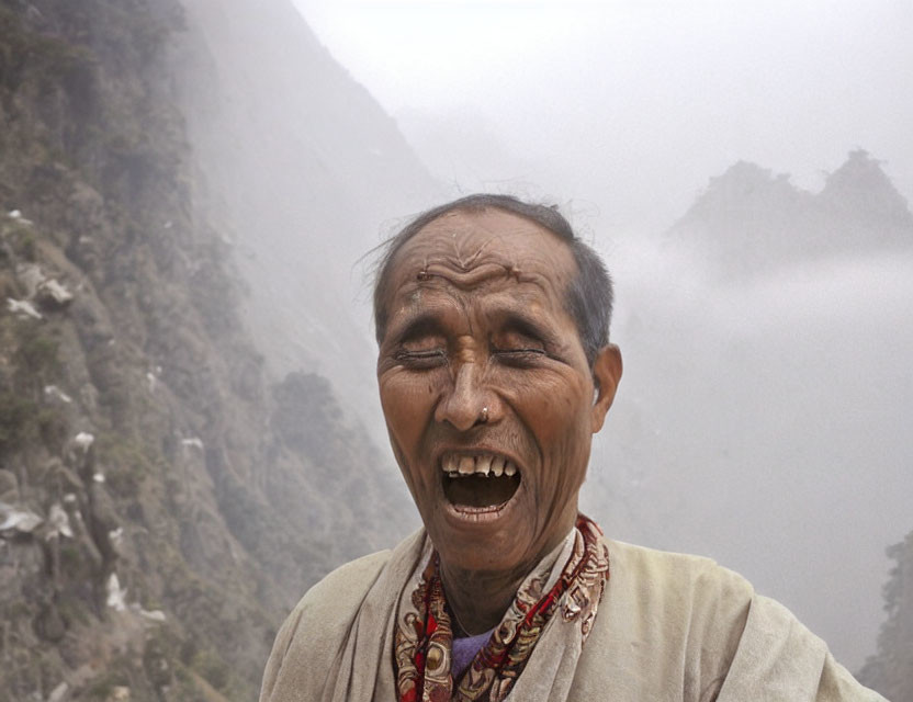 Elderly man smiling in front of misty mountains