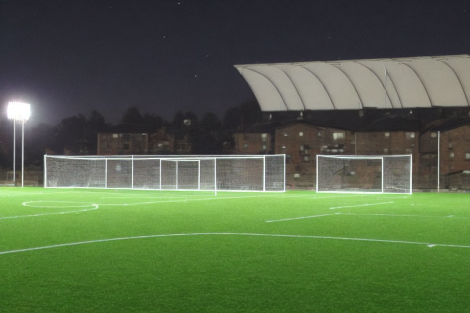 Deserted soccer field at night with goalpost and illuminated spotlights