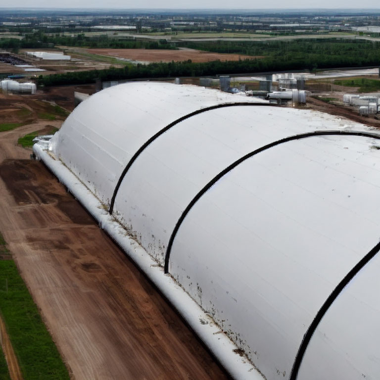 Large white industrial tent-like structures with curved roofs in aerial view.