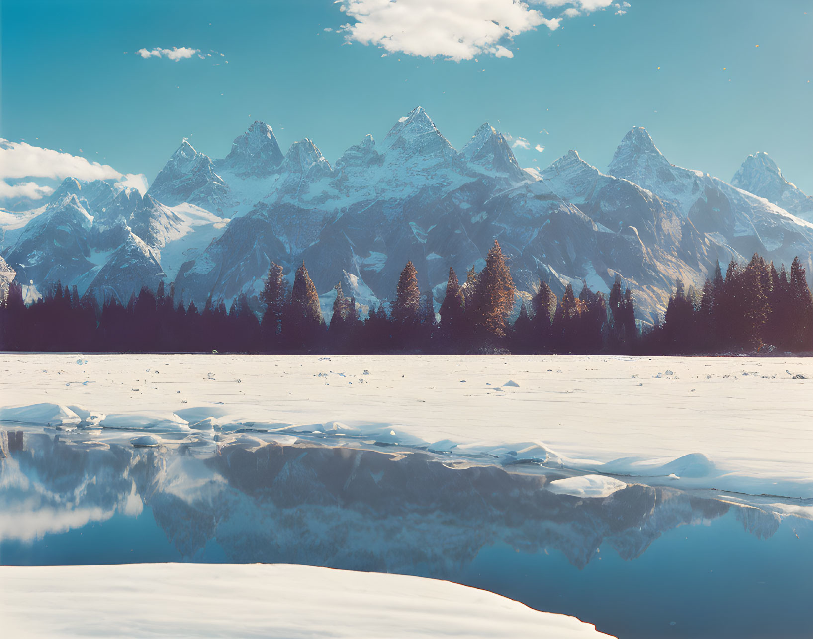 Snow-covered Foothills, Icy Lake, and Snow-Capped Peaks in Tranquil Winter Scene