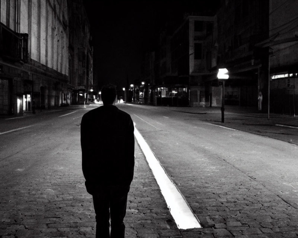 Solitary figure in deserted urban street at night