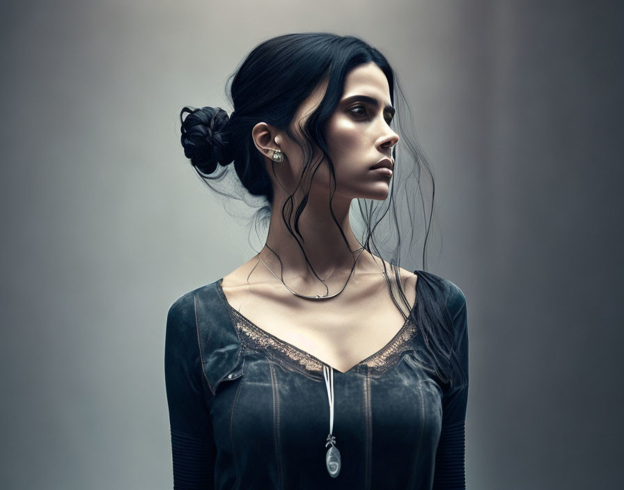 Dark-haired woman in black dress with pendant necklace and transparent neckline