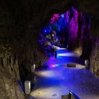 Mystical cave with purple and pink lights, blue water, rocks, and crystals