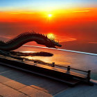 Dragon Sculpture Over Water at Sunset with Orange and Blue Skies