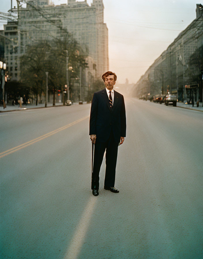 Man in suit with cane on empty sunlit city street