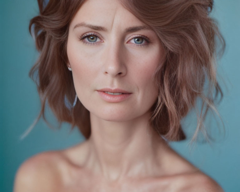 Portrait of woman with short wavy hair and blue eyes on turquoise background