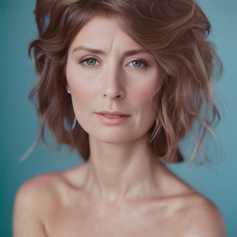 Portrait of woman with short wavy hair and blue eyes on turquoise background