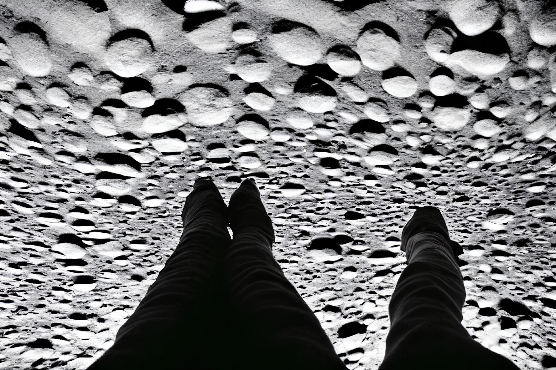Monochrome image of legs on pebbled surface with dramatic lighting