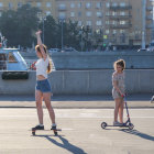 Two girls skateboarding on sunny street in casual attire