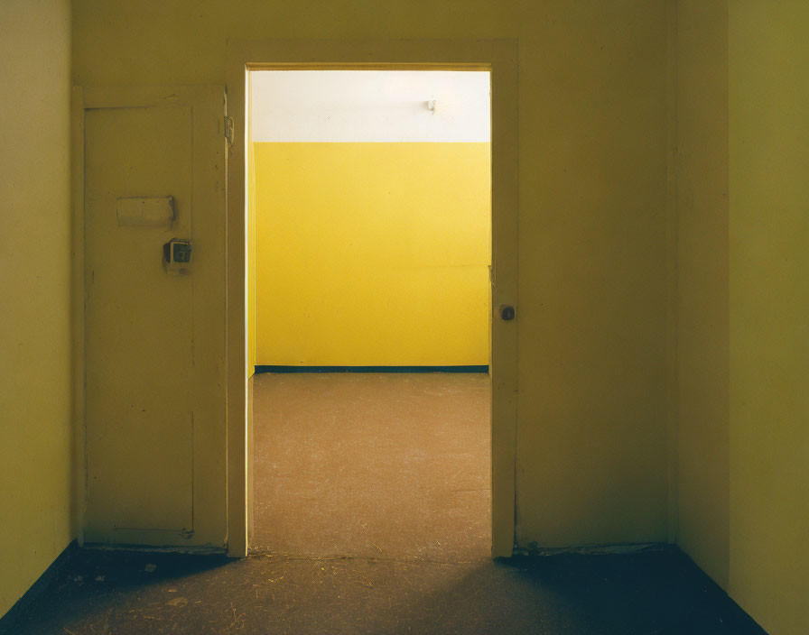 Open door to yellow-walled room in dimly lit corridor