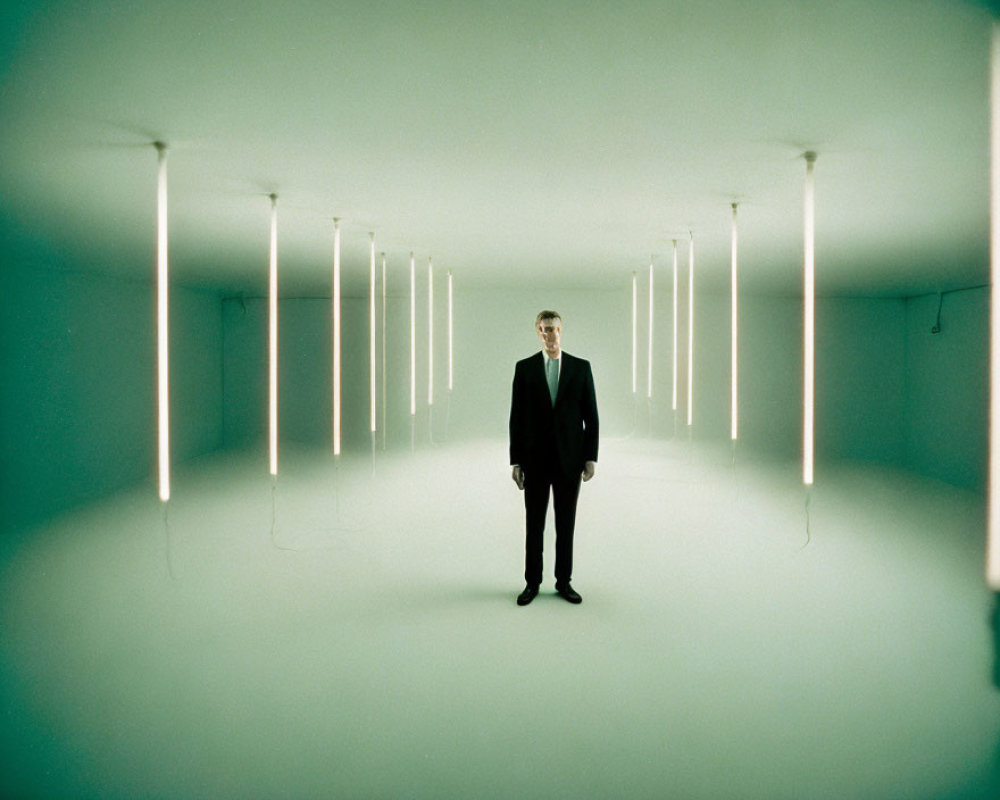 Symmetrical room with man in suit and vertical lights on greenish walls
