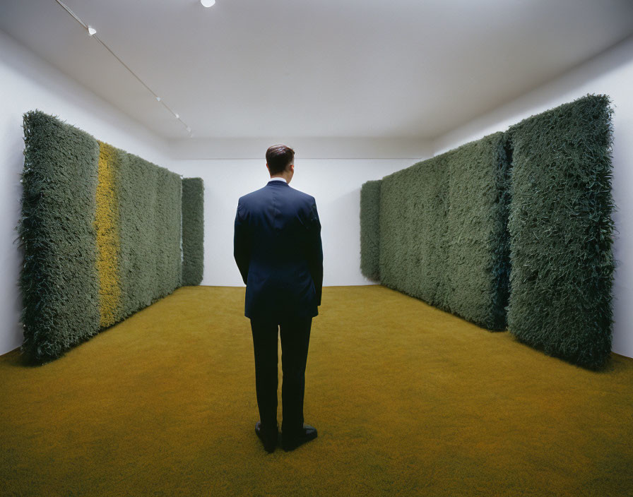 Man in dark suit in art gallery with green grass-like walls and yellow-green floor