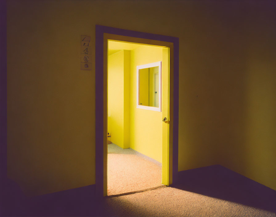Yellow-lit room seen through an open door casting warm glow and shadows