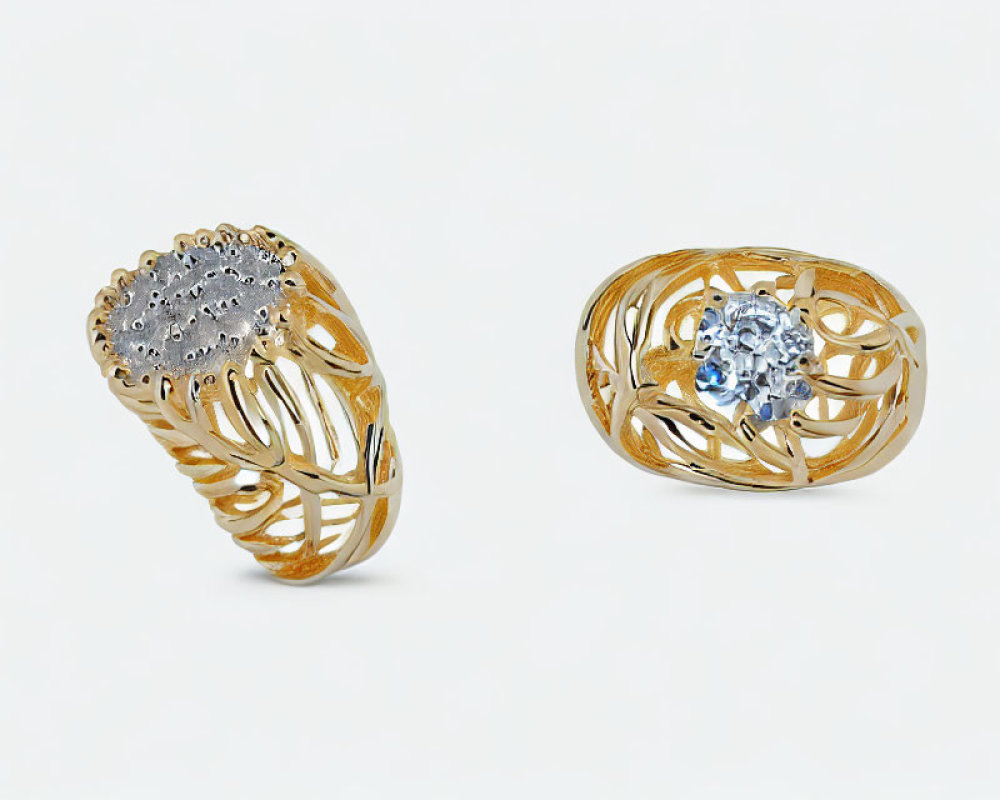 Ornate gold rings with filigree designs: diamonds and blue gemstone on white background