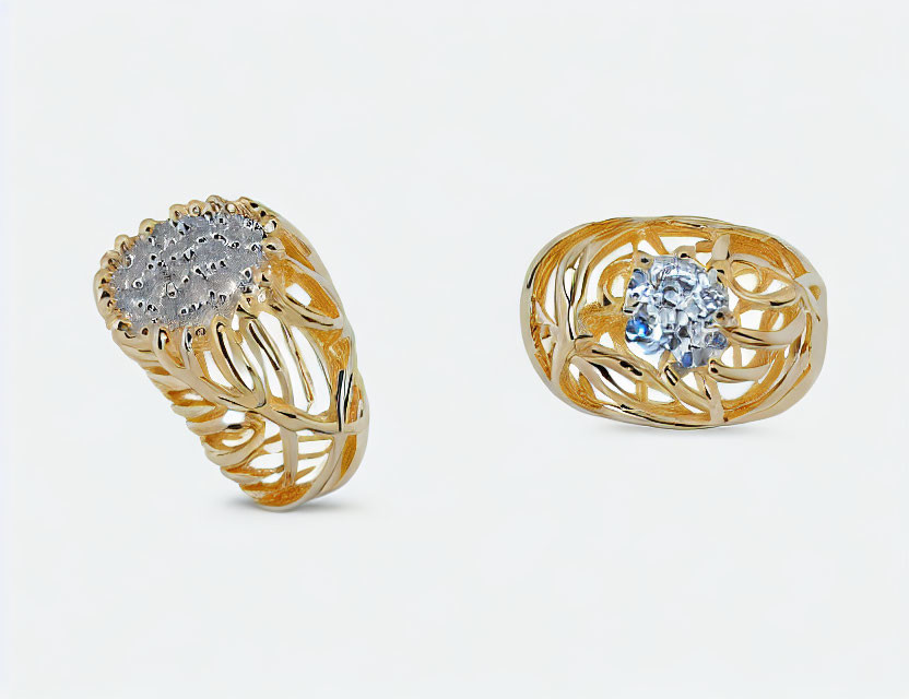 Ornate gold rings with filigree designs: diamonds and blue gemstone on white background