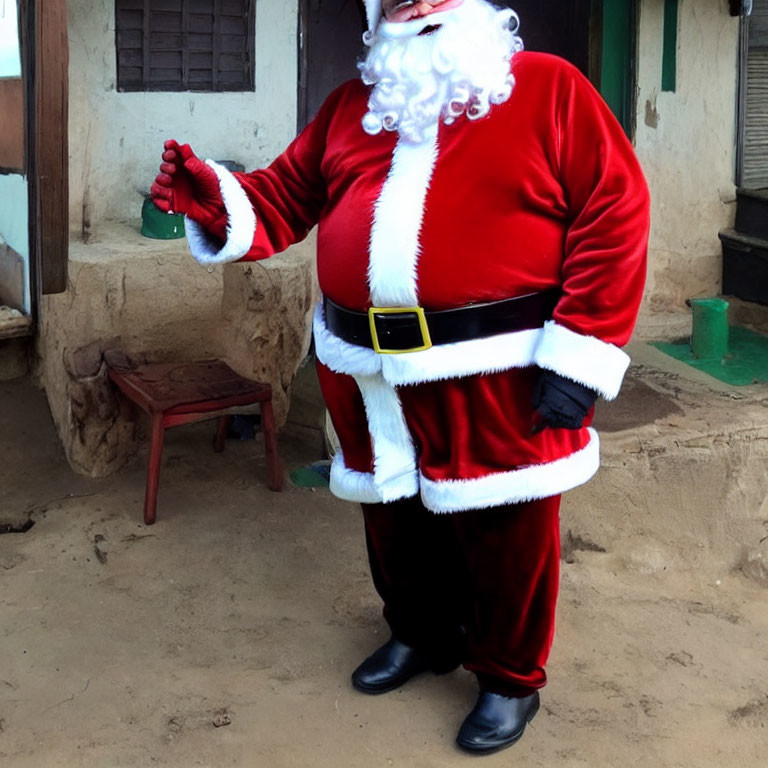 Santa Claus costume person with bell, stool, and building outdoors