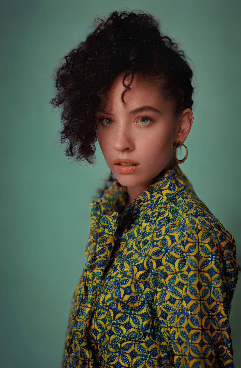 Curly-Haired Woman in Yellow Shirt on Teal Background