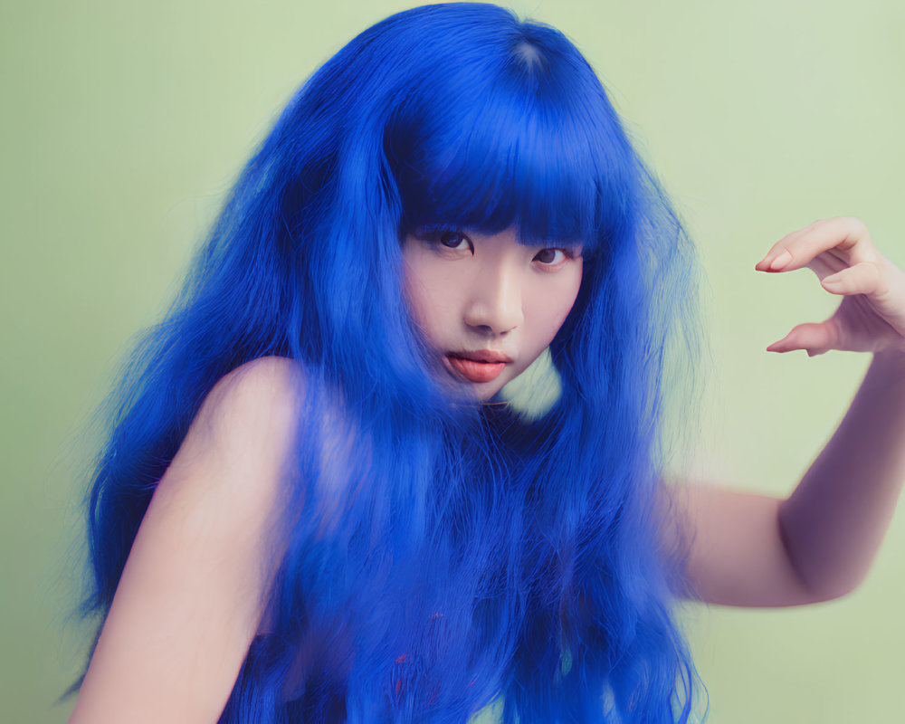 Vibrant Blue-Haired Person Posing Against Green Background