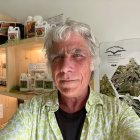 Elderly man in green shirt by cannabis display case