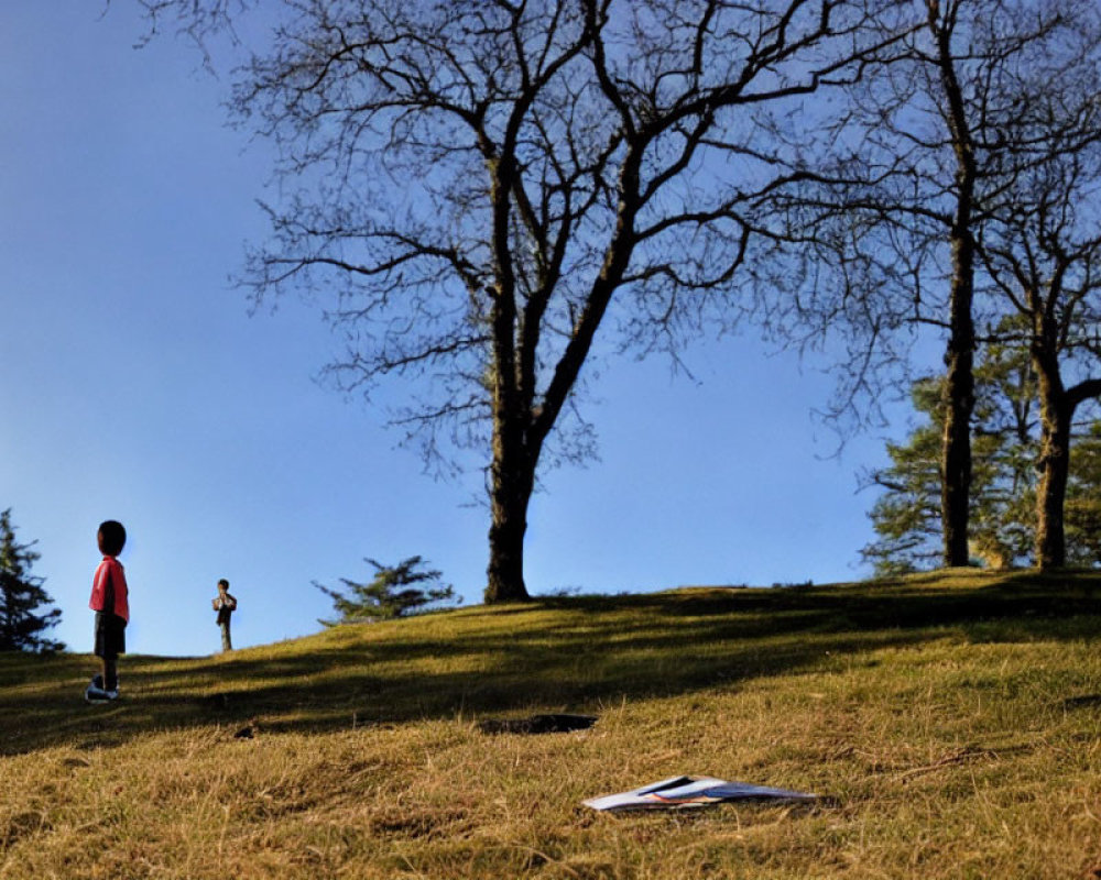Children on grassy hill with book under clear blue sky