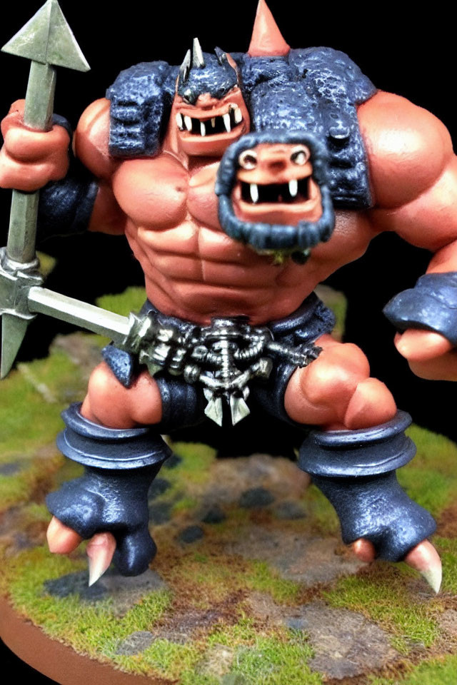 Dual-faced fantasy miniature figure in blue armor with spear and studded belt.