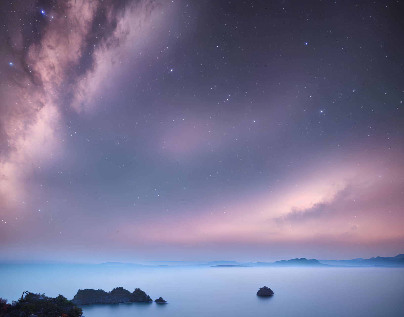 Twilight sky with Milky Way galaxy over calm sea and distant islands in blue to pink hues
