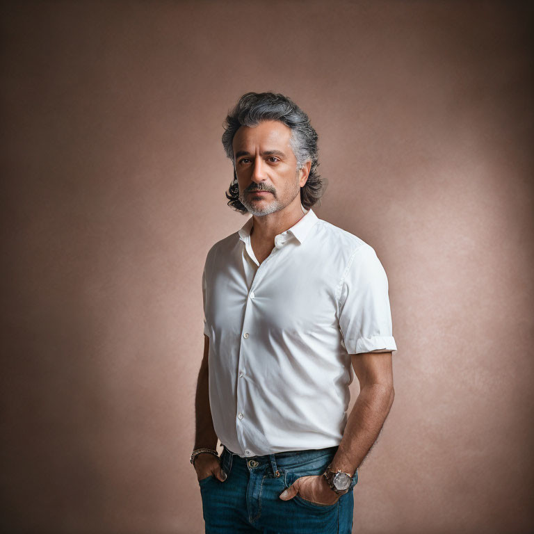 Gray-Haired Man in White Shirt and Jeans on Neutral Background