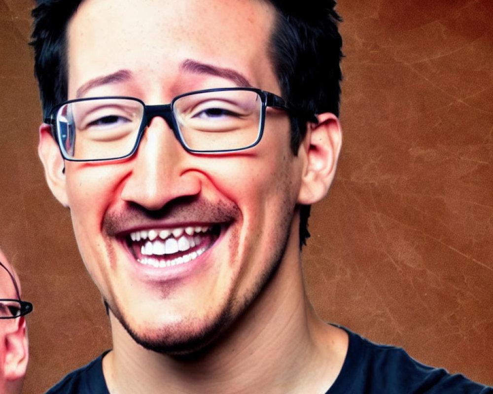 Smiling man with glasses and black shirt on brown textured background