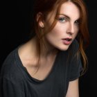 Woman with Red Hair and Blue Eyes in Dark Blouse on Black Background