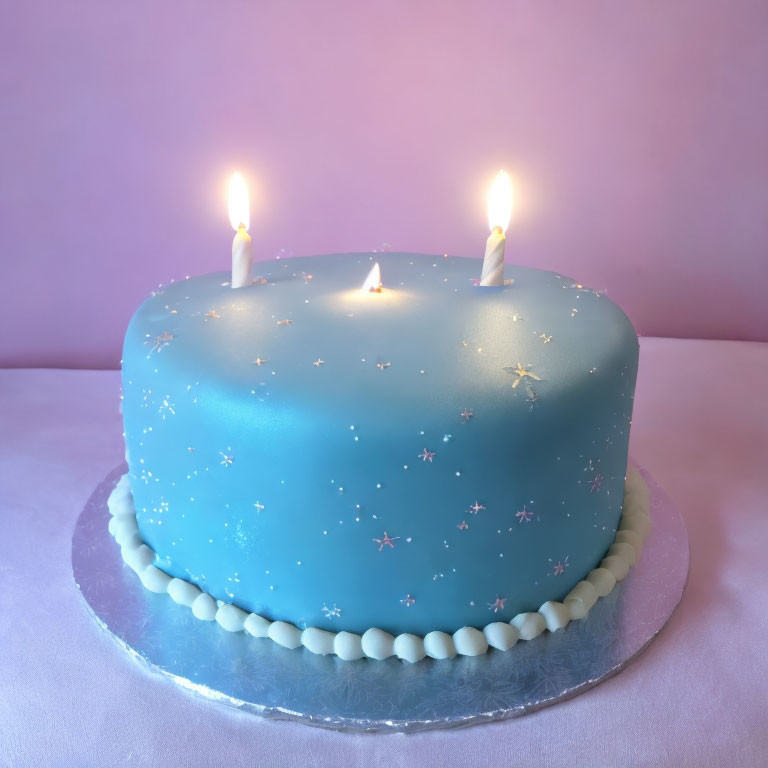 Blue Fondant Cake with Starry Design and Lit Candles on Pink Background