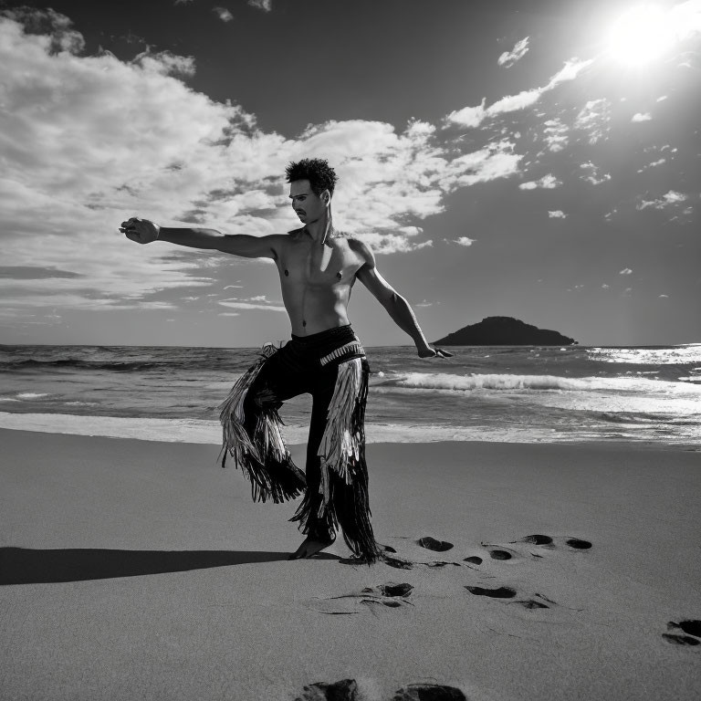 Male dancer in fringed pants poses on beach at sunset