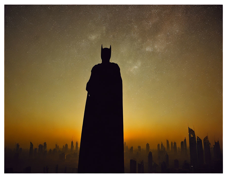 Person in Batman costume silhouette against city skyline under starry night.