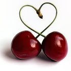 Glossy Red Cherries Intertwined in Heart Shape on White Background