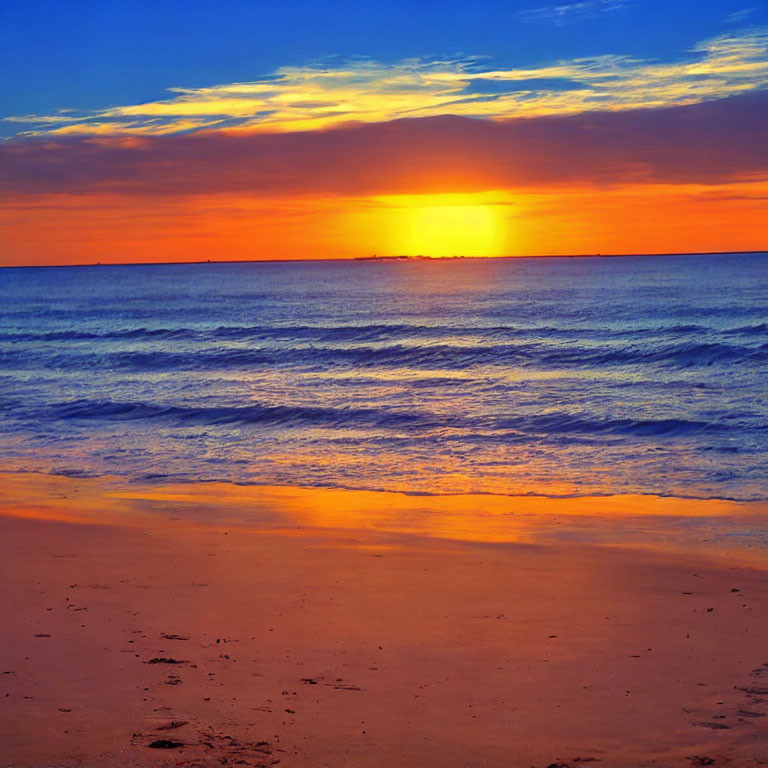 Vibrant sunset with orange and blue hues over calm ocean beach