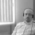 Man in headphones with focused expression near window in monochromatic filter