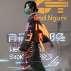 Futuristic image of person with neon signs, mask, black jacket & cyberpunk vibe