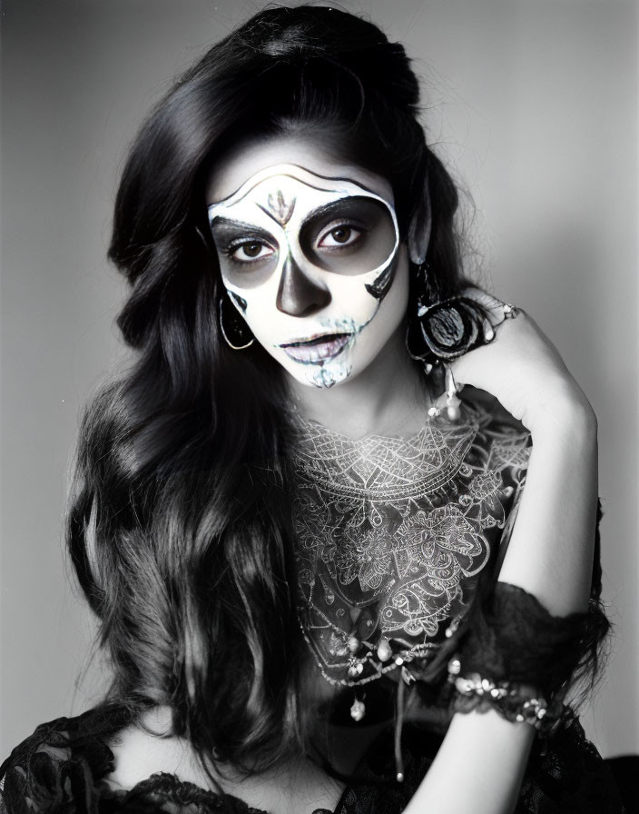 Half-face dramatic skull makeup with black, white, and blue designs and flowing dark hair.