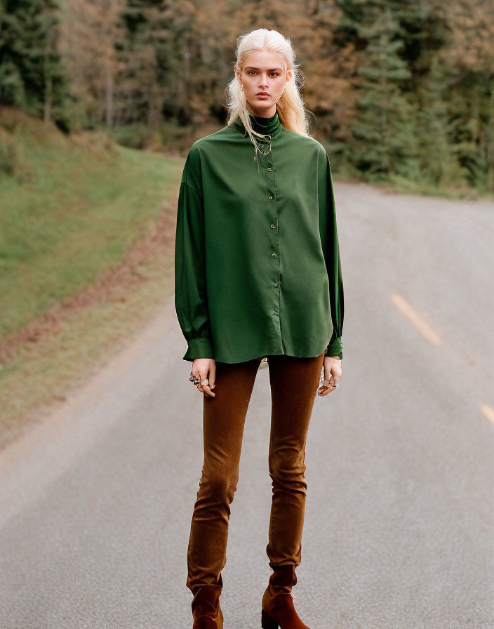 Blonde person in green blouse and brown pants on forest road