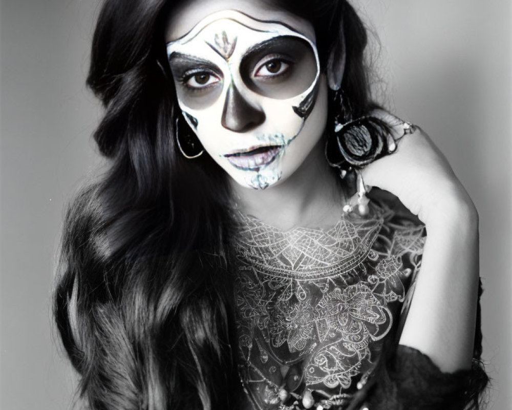 Half-face dramatic skull makeup with black, white, and blue designs and flowing dark hair.