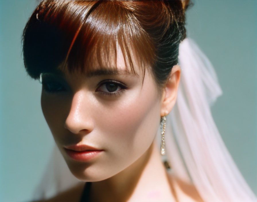Portrait of woman with auburn hair and white veil, wearing earrings