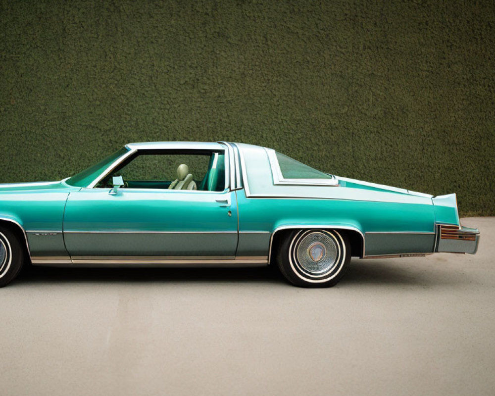 Teal Classic Car with White Roof and Chrome Details Against Green Wall