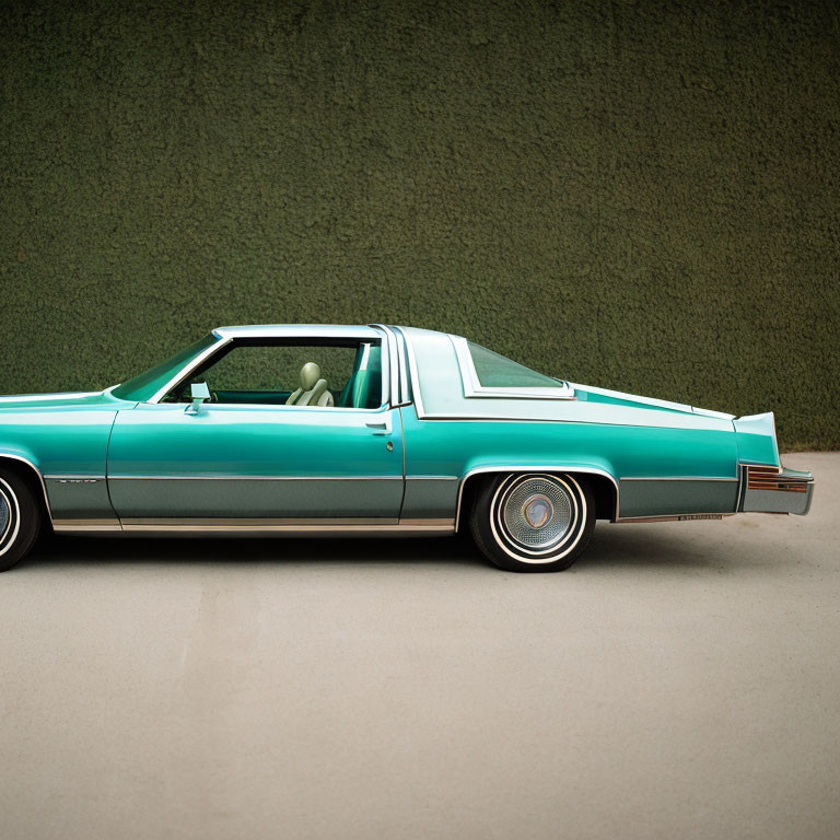 Teal Classic Car with White Roof and Chrome Details Against Green Wall