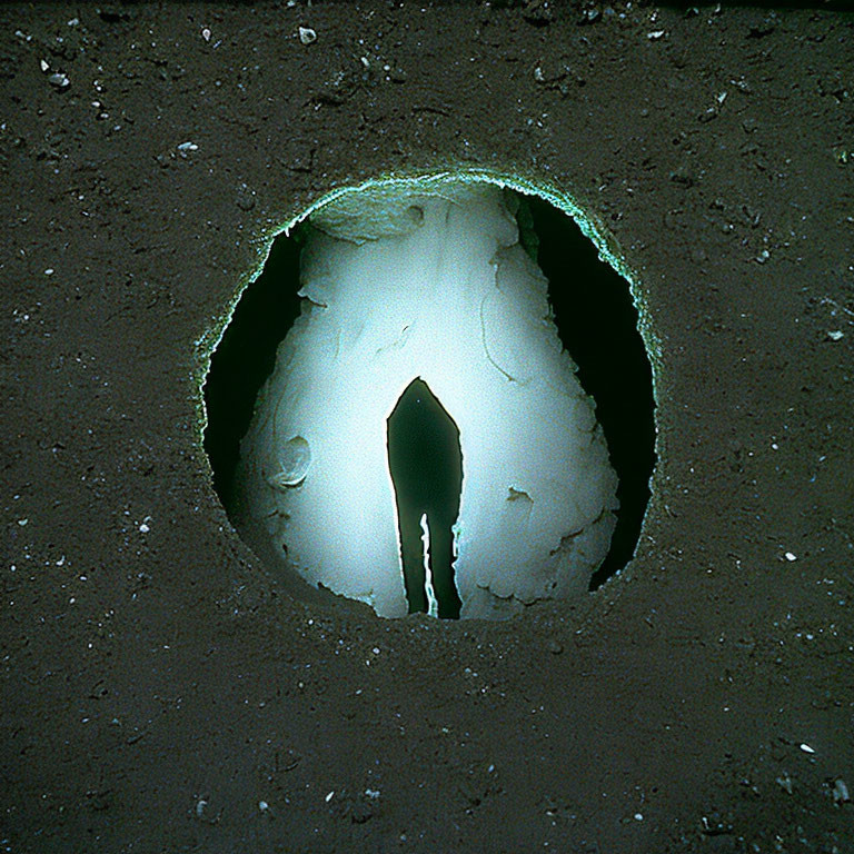 Circular Hole with Bright Interior and Jagged Edges: Entrance to Underground Cavern