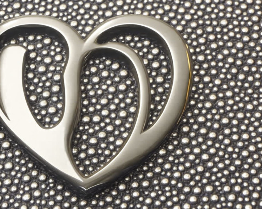 Silver Heart-Shaped Pendant on Textured Surface with Shiny Beads