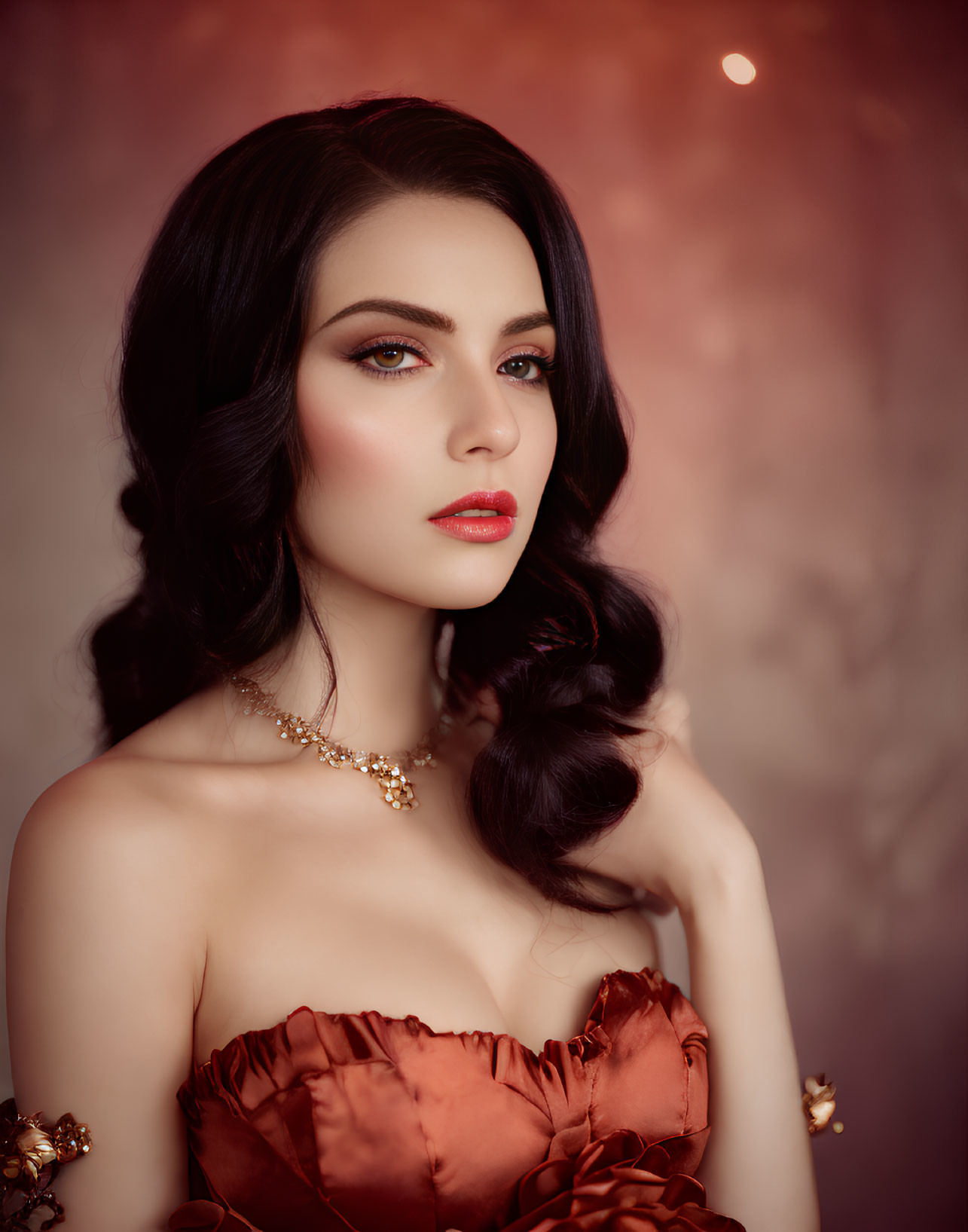 Dark-haired woman in red lipstick and dress posing elegantly on soft red backdrop.
