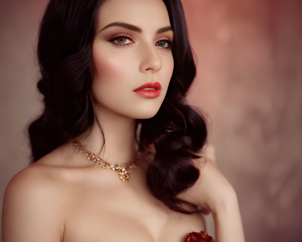 Dark-haired woman in red lipstick and dress posing elegantly on soft red backdrop.
