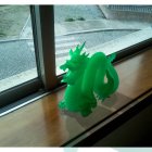 Detailed Green Dragon Sculpture on Wooden Ledge with Intricate Dragon Artwork on Frosted Glass