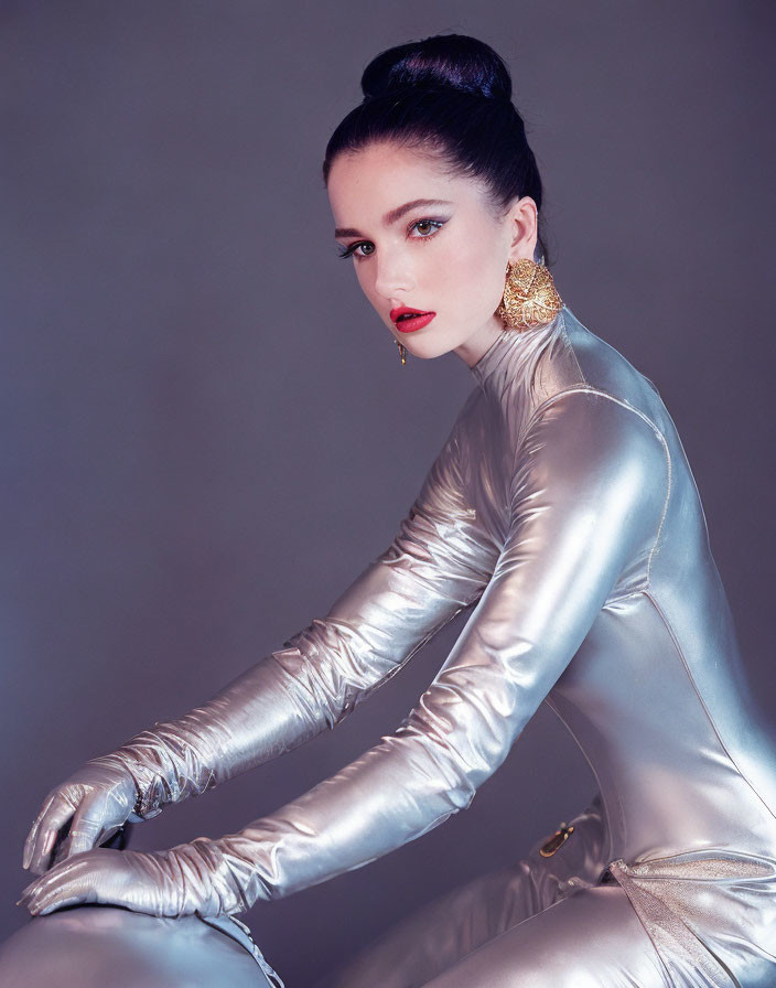 Woman in red lipstick and gold earrings poses in metallic silver bodysuit